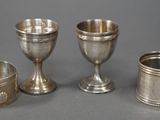 trois gobelets et tasses en argent posés sur une table