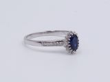 an oval sapphire and diamond ring on a white surface