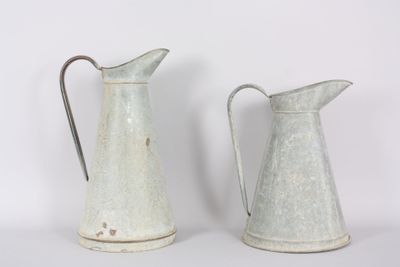 two metal pitchers sitting next to each other on a table