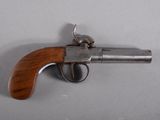 un vieux pistolet avec une poignée en bois sur une surface blanche