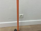 an orange lamp on a wooden floor next to a white wall