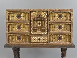 une commode dorée posée sur un socle en bois