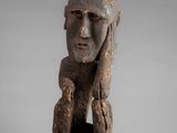 an old wooden sculpture of a man with his hands on his face