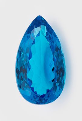 une topaze bleue en forme de larme, facettée, sur fond blanc