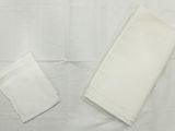 deux serviettes blanches posées sur une nappe blanche, sur une table