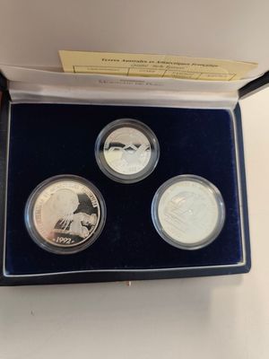 a box of three silver coins with a picture of a man on it