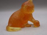 une petite figurine de chat orange posée sur une surface blanche
