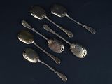 six silver spoons on a black surface with a black background