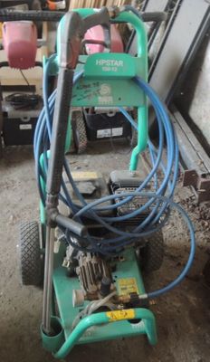 une machine verte à laquelle est raccordé un tuyau, dans un garage