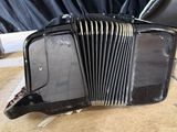 an old black accordion sitting on top of a wooden floor