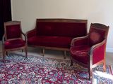 un canapé rouge et deux fauteuils dans un salon