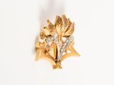 a close up of a gold brooch with leaves and flowers
