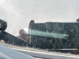 a person holding a cell phone in the rear view mirror of a car