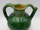 a green vase that is sitting on a white surface
