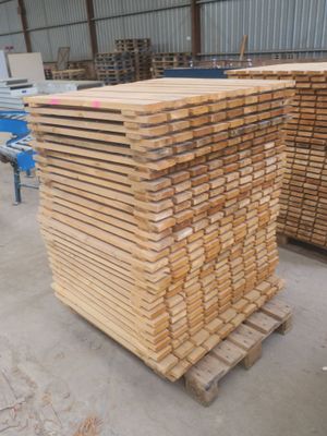 plusieurs piles de bois empilées sur des palettes dans un entrepôt