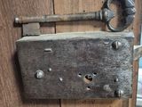 a metal latch on a wooden door that has a key on it