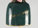 a hand holding a green bell with a gold writing on it