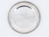une assiette en argent entourée d'une corde torsadée sur un fond blanc