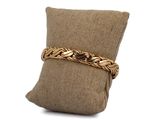an image of a gold bracelet on a pillow on a white background