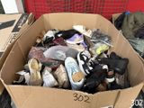 une boîte en carton remplie de chaussures posée par terre