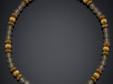 a gold and grey beaded necklace with glass beads on a black background