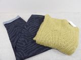 two pairs of pants and a sweater sitting on a bed