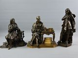 trois figurines en bronze représentant un homme et une femme assis à une table
