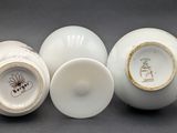 three white porcelain vases sitting on top of a gray surface