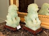 two jade statues sitting on a table in front of a mirror