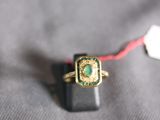 a gold ring with a green stone on it