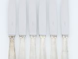 un ensemble composé de cinq couteaux en métal argenté et d'un porte-couteaux