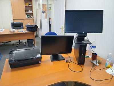 un bureau sur lequel se trouvent deux écrans et une imprimante