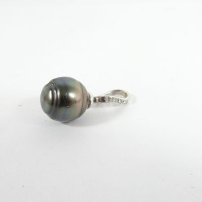 un gros plan d'une bague en perle noire posée sur une surface blanche