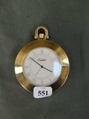 a gold pocket watch with a white face on a table