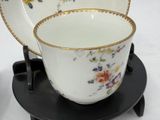 a cup and saucer sitting on a stand on a table