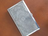 a silver book sitting on top of a leather table next to a cup of coffee