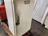 a white refrigerator sitting on a pallet in a warehouse