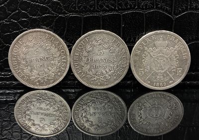 trois pièces d'argent posées l'une à côté de l'autre sur une surface noire