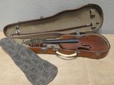 un violon dans son étui, posé sur une table à côté d'une chaussette