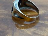 silver ring with black stone on a wooden surface