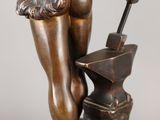 an antique bronze statue of a man holding a hammer and an anvil