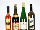 four bottles of wine are lined up on a white surface