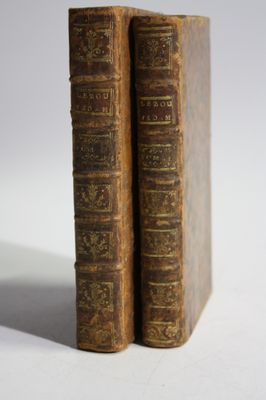 two old books sitting on top of each other on a white surface