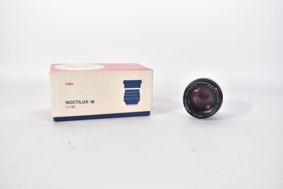an old camera lens sitting next to a box on a white surface