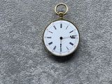 une petite montre de poche en or avec des chiffres romains