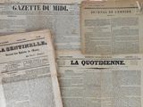 Plusieurs vieux journaux sont empilés les uns sur les autres sur une table