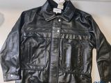 une veste en cuir noir posée sur une table blanche