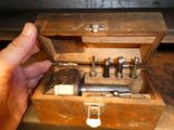 a person holding a small tool in a wooden box