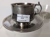 a silver cup and saucer on a silver plate