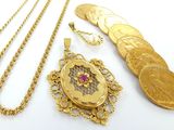 plusieurs colliers en or et une pièce d'or posés sur une surface blanche